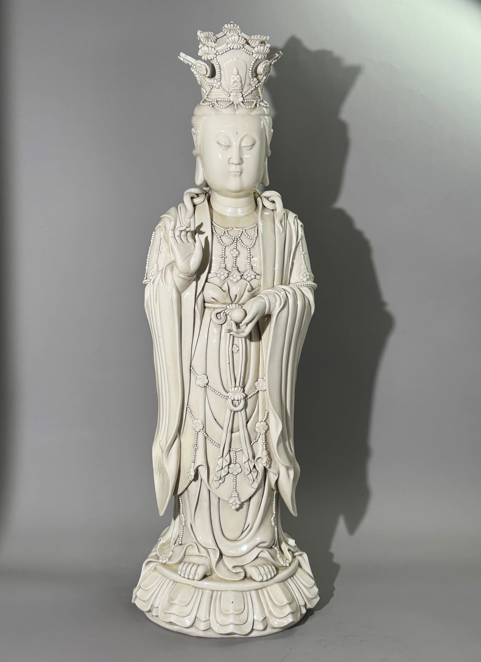Large Chinese Dehua Blanc-de-Chine Guanyin: Large Chinese Dehua Blanc-de-Chine Standing Guanyin Figure. A substantial blanc-de-chine porcelain figure of Guanyin standing upon a moulded lotus pedestal. She wears an ornate multi-lobed crown inset