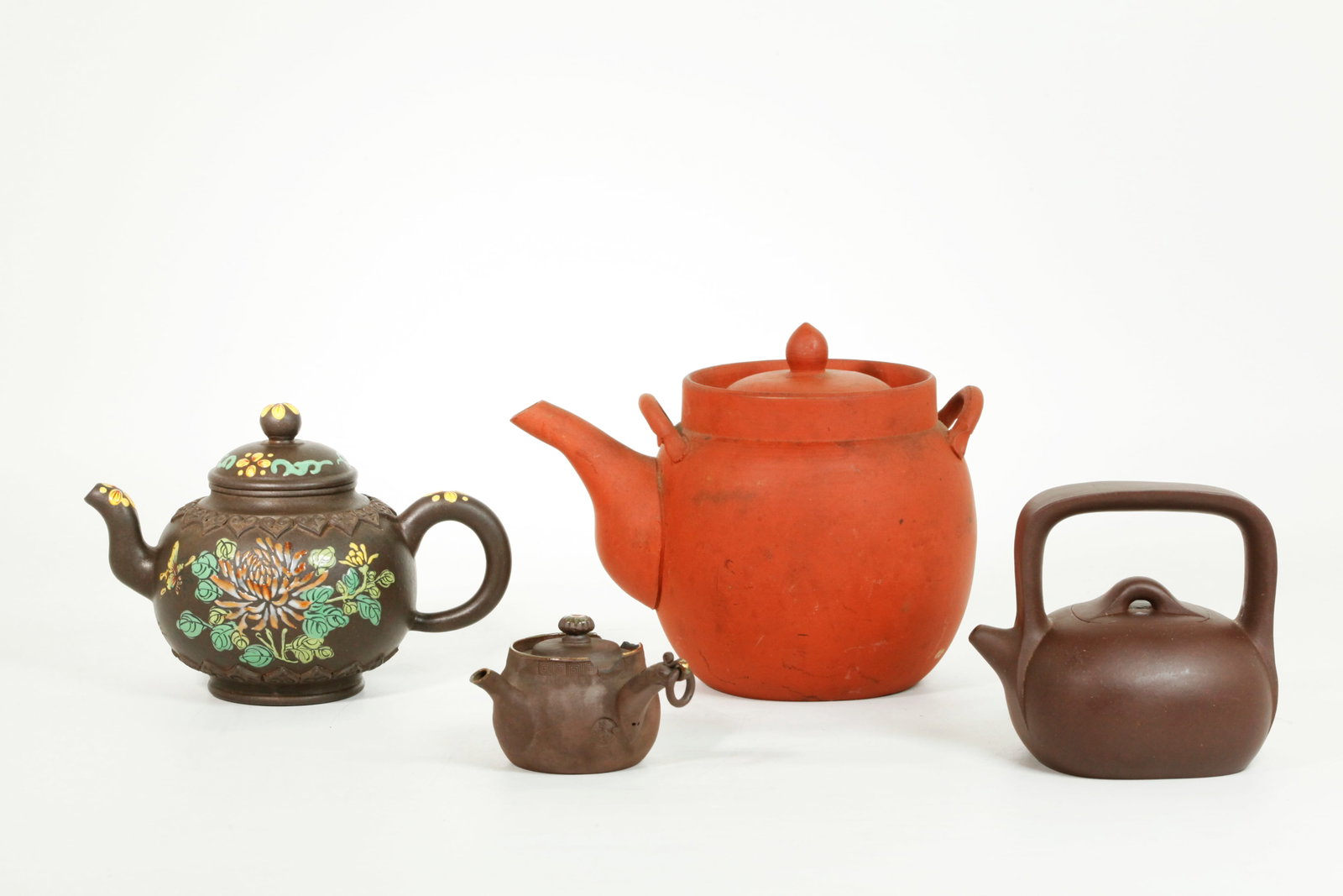 2 Chinese Yixing Zisha Teapots; 2 Brown Japanese: 2 Chinese Yixing Zisha Teapots, the larger with enameled flowers on dark clay and with an incised mark under the spout with seal to bottom, and a small wide strap overhead handle teapot with seal to b