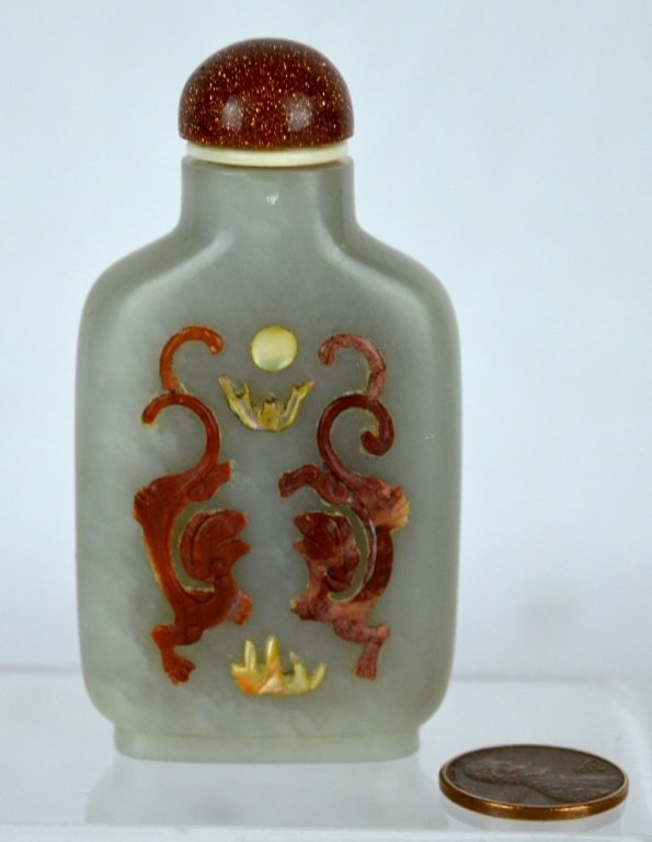Embellished Chinese Jade Snuff Bottle: Chinese jade snuff bottle, the sides embellished with carved soapstone dragons and shell pearls. Goldstone top. Height with top 3 inches (7.5 cm) Good condition Any condition statement is given as a c