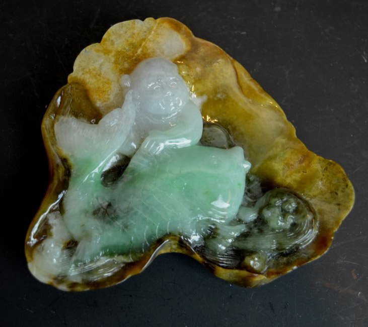 Chinese Multi-colored Jadeite Carving: Chinese Multi-colored Jadeite Carving of a boy on a fish all on a large lotus leaf. Width 3 1/4 inches (8.5 cm.). Good condition.