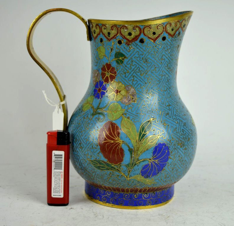 Unusual 18th C Chinese Cloisonne Jug Strap Handle: Unusual 18th C Chinese Cloisonne Jug with a Strap Handle. Two dents to body with related loss of glass, glass loss to top of strap handle. Provenance: An Old Virginia Beach Collection. Height 8 inches