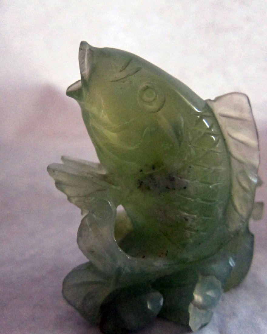 Jade or hard stone small carving of a fish, wood stand: Jade or hard stone nice carving of a fish. Good craftsmanship. On wooden stand. 3 inches tall and 2,75 inches wide. 4 inches tall with wood stand.