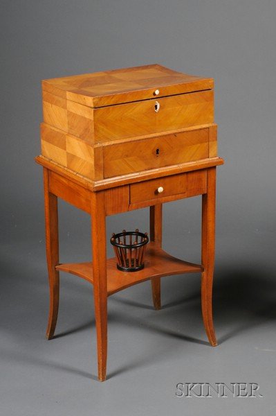 Biedermeier Part-ebonized Fruitwood Work Box on Sta: Biedermeier Part-ebonized Fruitwood Work Box on Stand, c. 1825, hinged lid with needlework paneled and fitted interior, base with frieze drawer, medial shelf with small yarn basket, splayed legs, ht. 