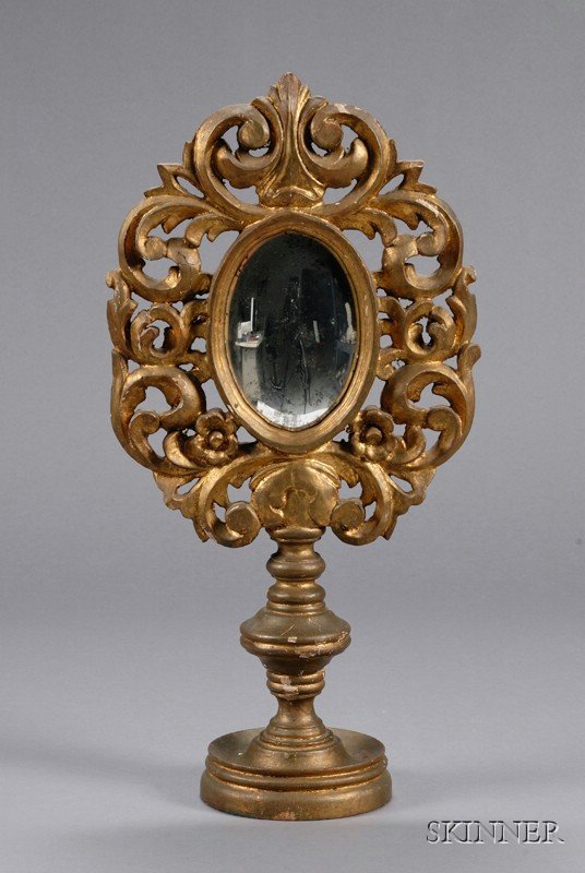 Baroque-style Carved Giltwood Ecclesiastic Convex: Baroque-style Carved Giltwood Ecclesiastic Convex Table Mirror, the oval convex mirror in oval scroll-carved frame, on knopped stem and dished foot, ht. 23 in.
