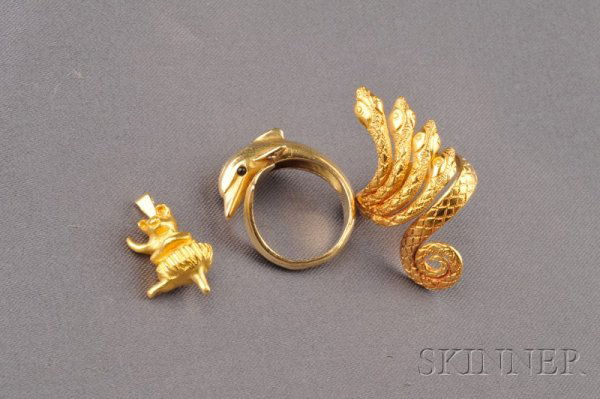 Three Jewelry Items, a 24kt gold ballerina pig, si: Three Jewelry Items, a 24kt gold ballerina pig, signed J.C., probably for Julius Cohen, a 22kt gold snake ring, and an 18kt gold dolphin ring, diamond melee accents, French maker's mark and export sta