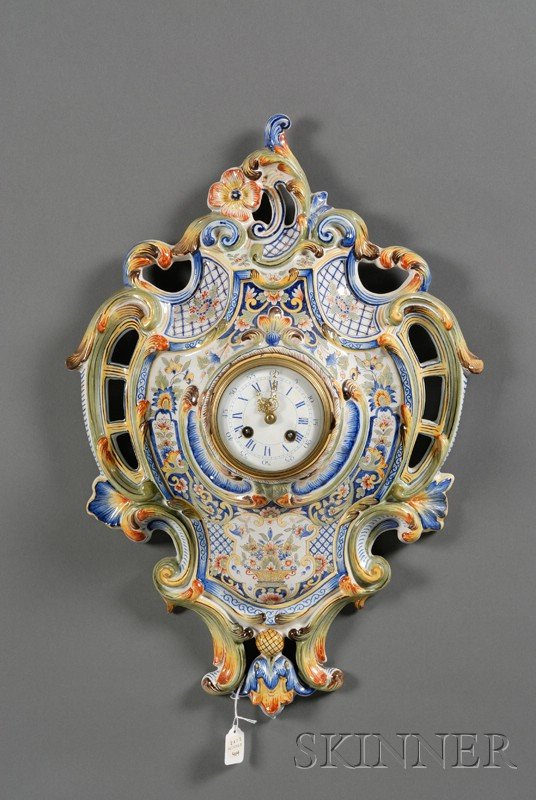 French Faience Rococo-style Wall Clock, France, 19: French Faience Rococo-style Wall Clock, France, 19th century, polychrome enamel decorated, scrolled openwork foliage bordering floral designs, enameled clock dial, lg. 22 1/2 in.