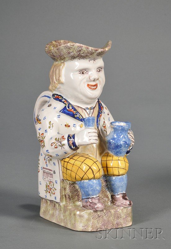 French Faience Toby Jug, France, 19th century, pol: French Faience Toby Jug, France, 19th century, polychrome enamel decorated, the seated figure modeled holding a cup and a pitcher, ht. 9 5/8 in.