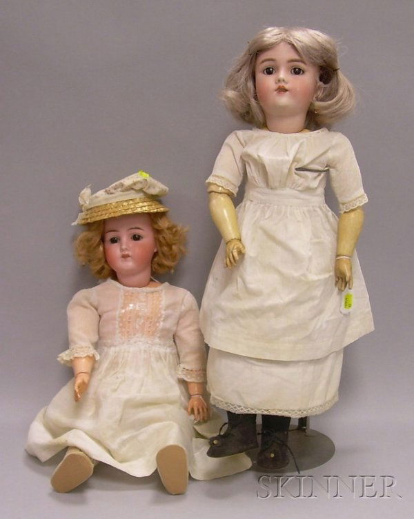 Two German Bisque Dolls in White Dresses, one bisq: Two German Bisque Dolls in White Dresses, one bisque head doll marked Germany B 4 with open mouth showing teeth, and weighted brown eyes, the other a Heinrich Handwerck/Simon Halbig doll with open mou
