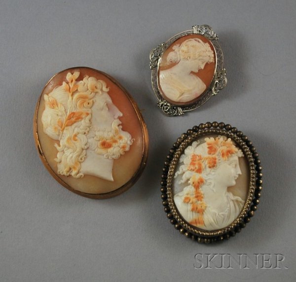 Three Shell-carved Cameo Brooches, framed in 14kt : Three Shell-carved Cameo Brooches, framed in 14kt yellow gold, 14kt white gold, and sterling silver.