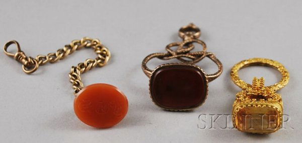 Three Watch Fobs, a 14kt gold and citrine fob, a 1: Three Watch Fobs, a 14kt gold and citrine fob, a 14kt gold and carnelian fob on a gold-filled chain, and a gold-plated hardstone fob.