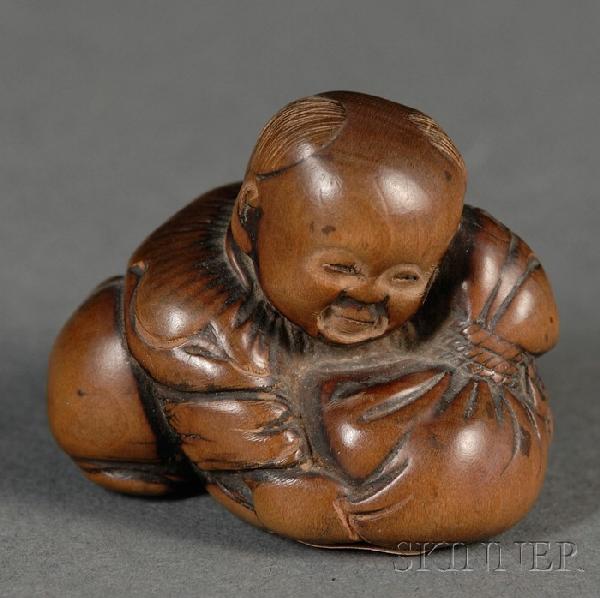 Boxwood Netsuke, Japan, 19th century, carved as a : Boxwood Netsuke, Japan, 19th century, carved as a chubby child holding a stuffed sack, signed, ht. 1 1/4, lg. 1 3/8 in.