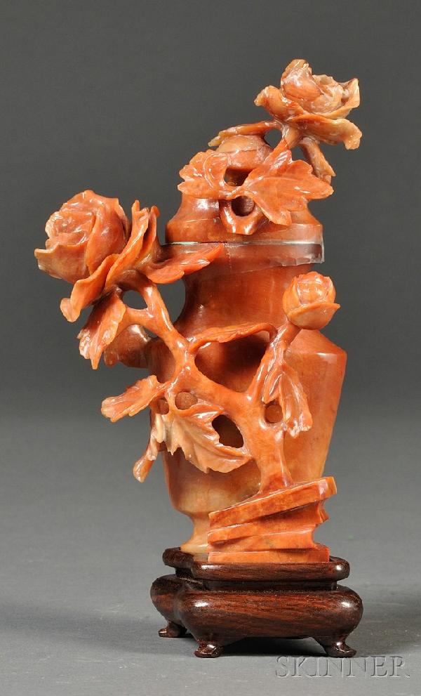 Carnelian Agate Vase and Cover, China, of flatten: Carnelian Agate Vase and Cover, China, of flattened hu shape, carved in high relief of rose branches issuing from rockwork to one side, continuing onto the cover, wood stand, ht. 6 3/4 in.