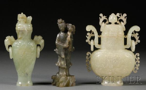 Three Bowenite Carvings, China, two covered hu va: Three Bowenite Carvings, China, two covered hu vases, the stone of pale celadon color, together with a carved figure of female Immortal standing on rockwork, with a lotus sprig in her hand, dark celad