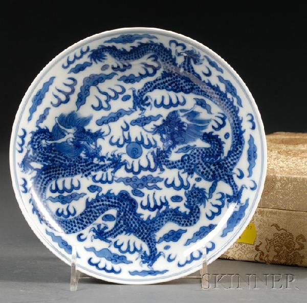 Blue and White Dish, China, painted as two scaly: Blue and White Dish, China, painted as two scaly dragons contending a flaming pearl amongst clouds, the exterior with four bats, Xianfeng six-character mark on the base, custom brocade box, dia. 7 1/4