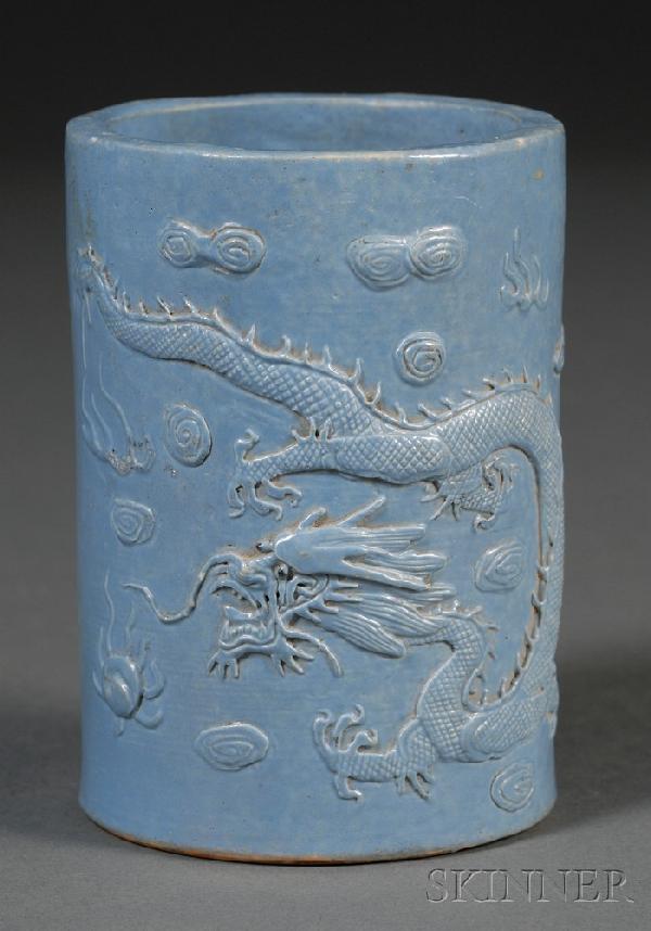 Blue Brush Pot, China, 19th century, cylindrical : Blue Brush Pot, China, 19th century, cylindrical shape with molded decoration of a sinuous dragon pursuing a flame pearl among clouds, reserved on a blue glazed ground, "Wang Bingrong" mark on the bas