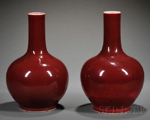 Pair of Sang-de-Boeuf Glazed Bottle Vases, China,: Pair of Sang-de-Boeuf Glazed Bottle Vases, China, with a globular bottle below a cylindrical neck, enameled on the exterior with crimson glaze thinning to white around the mouth-rim, the interior and 