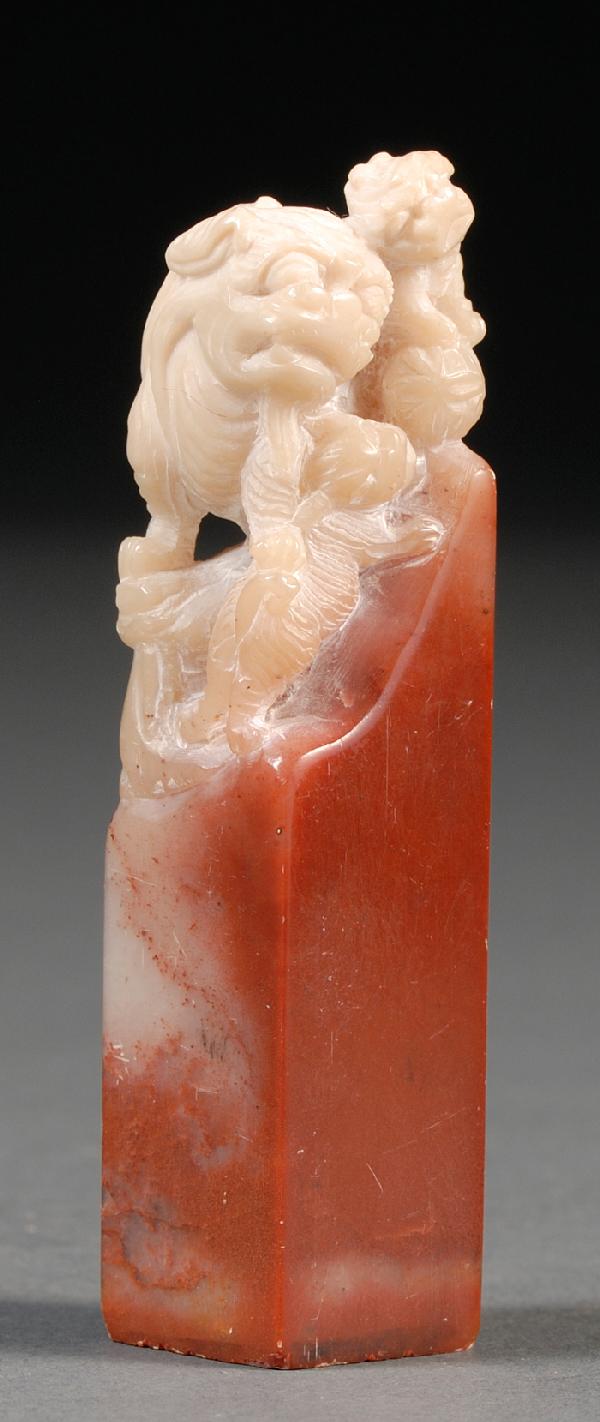 Carnelian Seal, China, of rectangular shape, the : Carnelian Seal, China, of rectangular shape, the crimson-colored body in contrast with the finial of white hardstone, well carved as a foo dog with two cubs playing a brocade ball, lg. 3 1/2 in.