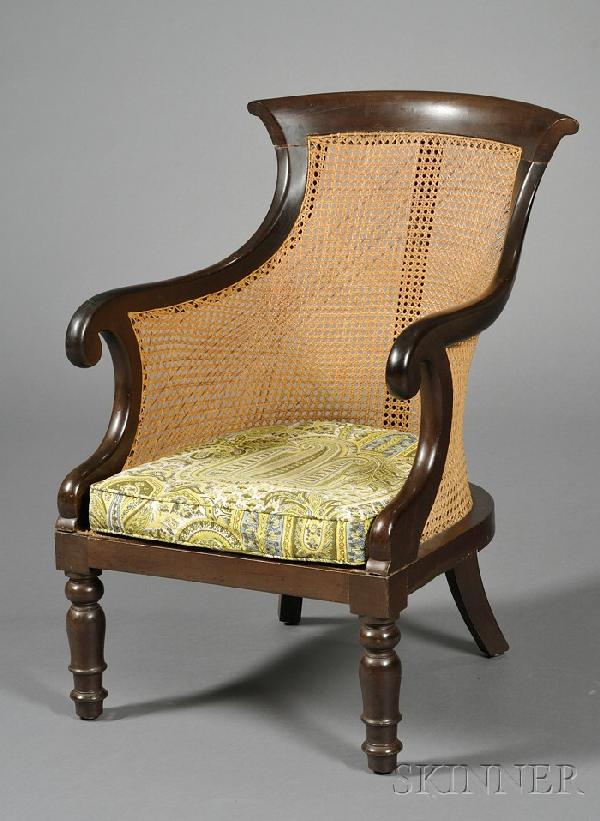 William IV Caned Mahogany Bergere, c. 1835, with c: William IV Caned Mahogany Bergere, c. 1835, with curved cresting and backrest with scrolled hand-holds, loose cushion seat on circular turned legs, seat ht. to cushion 14, wd. 19, dp. 21 in.