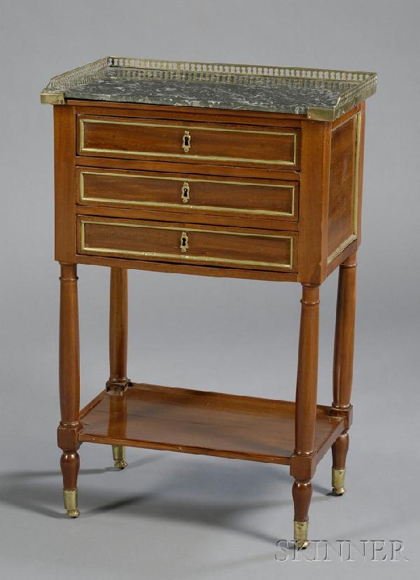 Louis XVI Brass-mounted Mahogany and Marble-top Ta: Louis XVI Brass-mounted Mahogany and Marble-top Table de Nuit, with three-quarter brass gallery about a white streaked black top and three drawers, on circular legs joined by a shelf stretcher, on cas