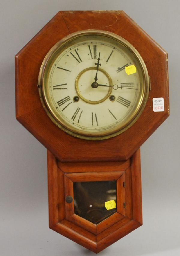 Oak Drop Octagon Wall Clock by Waterbury Clock C: Oak Drop Octagon Wall Clock by Waterbury Clock Company, with Roman numeral dial, printed maker's label, eight-day time and strike movement with pendulum, ht. 20 in.