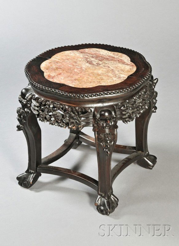 Rosewood Tabouret, China, 19th century, rounded for: Rosewood Tabouret, China, 19th century, rounded form with animal feet and foo dog heads at the shoulders, aprons carved and pierced with flowers, top inset with a red marble panel, dia. 20, ht. 17 1/2