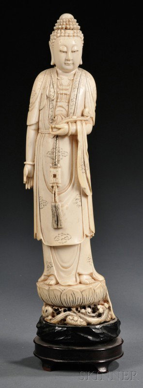 Ivory Buddha, China, 19th century, carved as the s: Ivory Buddha, China, 19th century, carved as the standing figure of Buddha atop a lotus stand, holding a ruyi scepter in his left hand, with incised cloud patterns to his robe, wood stand, ht. 11 1/4 