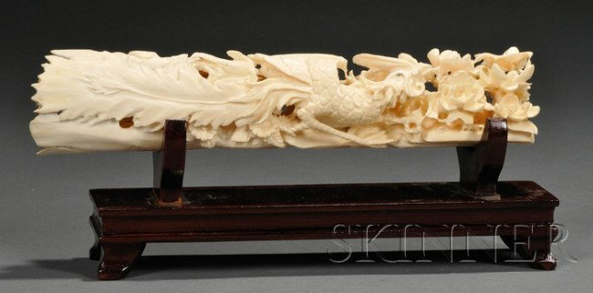 Ivory Carving, China, 19th century, carved and pie: Ivory Carving, China, 19th century, carved and pierced with a phoenix travelling amongst peony branches and ruyi clouds, wood display stand, lg. 8 1/2 in.