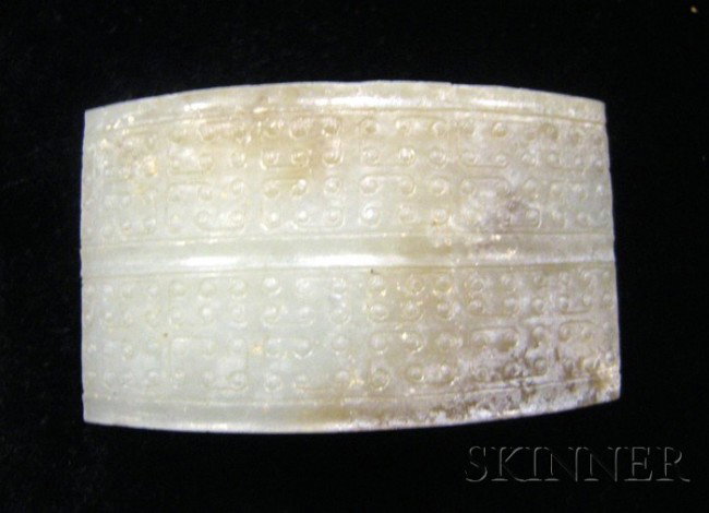 Jade Scabbard Slide, China, Warring States style,: Jade Scabbard Slide, China, Warring States style, of rectangular shape, the curved top carved with angular scrolls, pale celadon color with russet markings, 1 7/8 x 1 1/8 in.