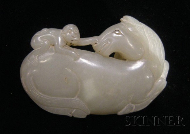 Jade Buckle, carved as a small monkey playing wit: Jade Buckle, carved as a small monkey playing with a recumbent horse, the stone of pale celadon color, lg. 3 1/8 in.