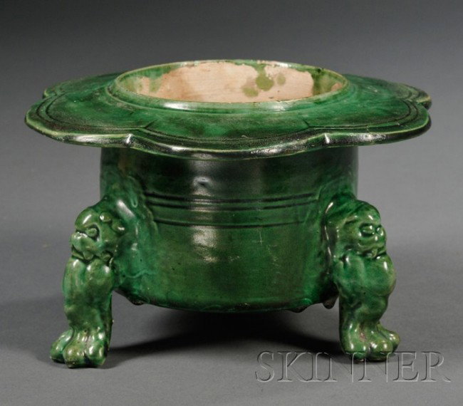 Green Glazed Brazier, China, Liao dynasty (907-11: Green Glazed Brazier, China, Liao dynasty (907-1125), the cylindrical body supported on tripod feet each molded into a standing lion, with broad everted petaled rim, the body carved with simple design