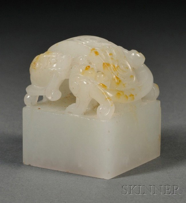 Jade Seal, China, the square sectioned seal surmo: Jade Seal, China, the square sectioned seal surmounted by high relief carving of foo dog group bearing a band of archaic scrolls, the stone of semi-translucent celadon white color with minor russet an
