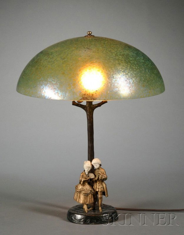 Table Lamp Bronze, ivory and art glass M. Brose, A: Table Lamp Bronze, ivory and art glass M. Brose, Austria, early 20th century Domed iridescent green oilspot shade in the manner of Loetz supported on a rustic tree-form shaft with two 18th century cos