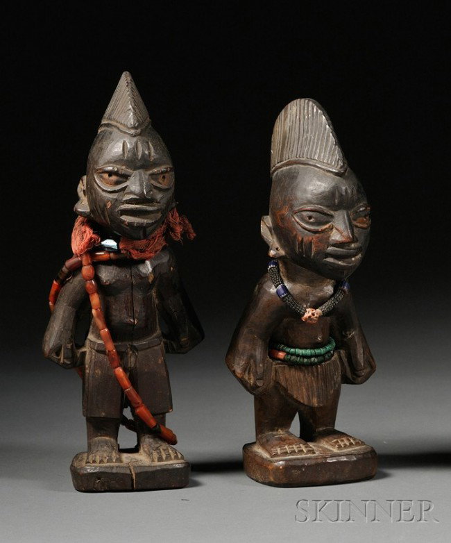 A Pair of African Carved Wood Ibeji Dolls, Yoruba,: A Pair of African Carved Wood Ibeji Dolls, Yoruba, a man and woman, the man is wearing European shorts, ht. to 10 in.