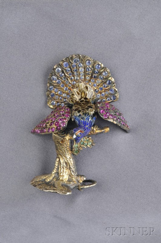 Silver-gilt Enamel and Gem-set Figural Objet, desi: Silver-gilt Enamel and Gem-set Figural Objet, designed as a peacock with polychrome enamel body and articulated wings, set with cushion-shape sapphires and rubies, perched on a stump with emerald leaf