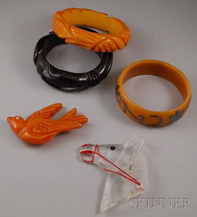 Group of Bakelite Jewelry, two carved bangles, a m: Group of Bakelite Jewelry, two carved bangles, a metal overlay bangle, and a carved bird brooch, together with a Lucite horse head brooch.