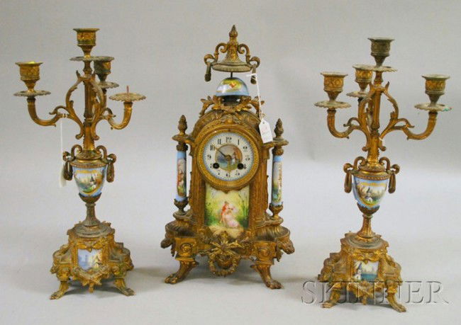 Three-piece French Clock Garniture, the clock with: Three-piece French Clock Garniture, the clock with spelter case, enameled panels and Arabic numeral dial, flanking candle holders of similar material and eight-day time and strike spring-powered movem