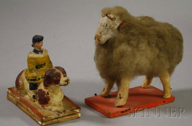 Papier-mache Child and Dog Figural Squeak-toy and: Papier-mache Child and Dog Figural Squeak-toy and Sheep Pull-toy, Germany, late 19th/early 20th century, the squeak-toy with a boy seated on a reclining spaniel, mounted on a bellows; a wool and hide