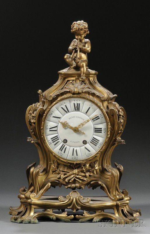 Henry Dasson Gilt-bronze Mantel Clock, France, c. 1: Henry Dasson Gilt-bronze Mantel Clock, France, c. 1880, the case with scrolling and foliage, figural finial with a cherub playing pipes, enameled dial inscribed Henry Dasson Paris, ht. 22 1/4 in.