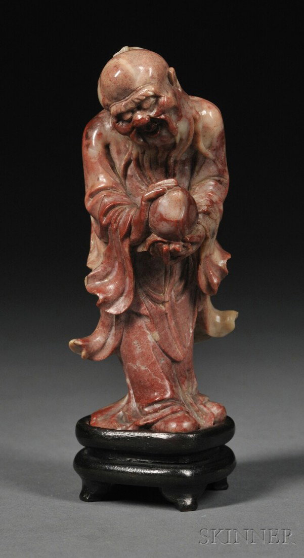 Soapstone Immortal, China, 18th/19th century, fine: Soapstone Immortal, China, 18th/19th century, finely carved as the standing figure of an Immortal holding a peach in both hands, wood stand, ht. 4 3/4 in.