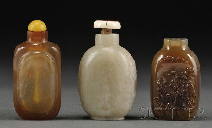 Three Snuff Bottles, China, 19th century, an oblo: Three Snuff Bottles, China, 19th century, an oblong agate bottle with relief carving of an Immortal and a deer, an ovoid jade bottle flanked by animal head lugs, and an agate bottle with a raised pane