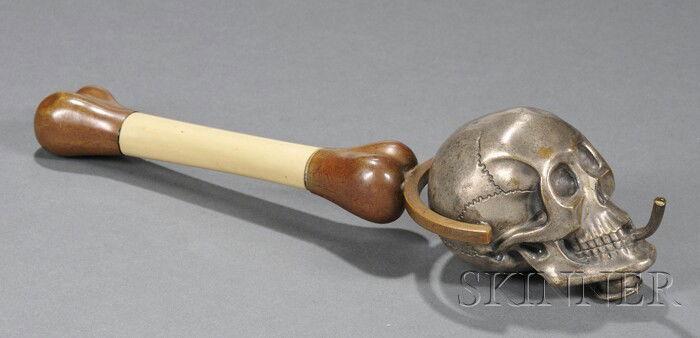 Skull and Bone Hand Lamp Patinated metal and resin: Skull and Bone Hand Lamp Patinated metal and resin 20th century Silvered metal skull font with threaded cap on filler and small burner issuing from mouth swivels on a bronze patinated bone-form shaft,