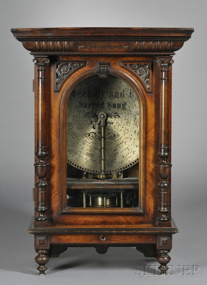 Polyphon 19-inch Coin Operated Disk Musical Box, t: Polyphon 19-inch Coin Operated Disk Musical Box, the figured walnut case with flat roof cornice, carved dentils and marked Polyphon in the center, glazed and hinged door, drawer and turned feet, iron 