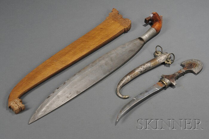 Two Bladed Weapons, a Moroccan Jambiya or Koumaya : Two Bladed Weapons, a Moroccan Jambiya or Koumaya dagger with 8 1/4-inch curving double-edged blade, and engraved mounts on wooden handle with similarly engraved scabbard; and a South Philippine Baron