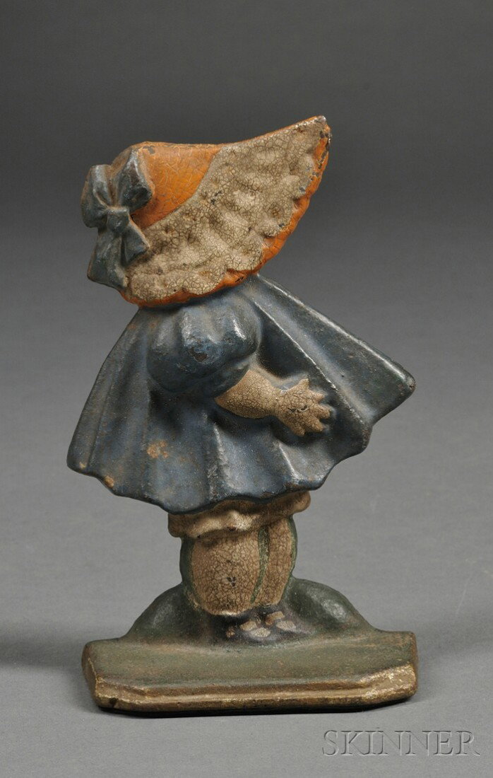Painted Cast Iron Sunbonnet Baby Doorstop, America: Painted Cast Iron Sunbonnet Baby Doorstop, America, early 20th century, original paint, the figure wearing a red bonnet with white lace trim and blue bow, and a blue dress, raised "72" mark on back, (