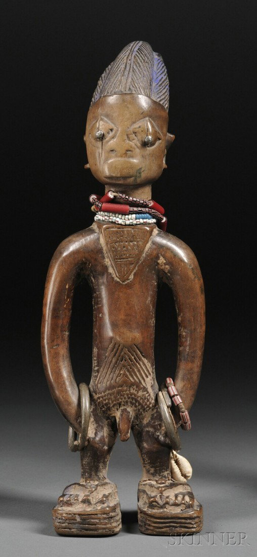Yoruba Carved Wood Ibeji, the male form with incise: Yoruba Carved Wood Ibeji, the male form with incised coiffure, trade bead, brass rings, and cowrie shell attachments, traces of blue pigment, (much wear), ht. 11 1/2 in.