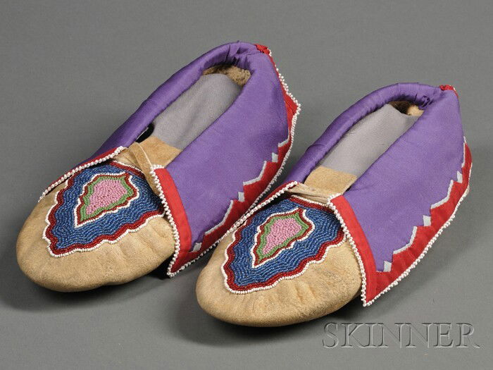 Delaware Beaded Hide Moccasins, c. 1930s, made by: Delaware Beaded Hide Moccasins, c. 1930s, made by Minnie Fouts, with multicolored abstract foliate design on the vamp, the cuffs with silk applique and edged with white seed beads, lg. 11 in. Provenan
