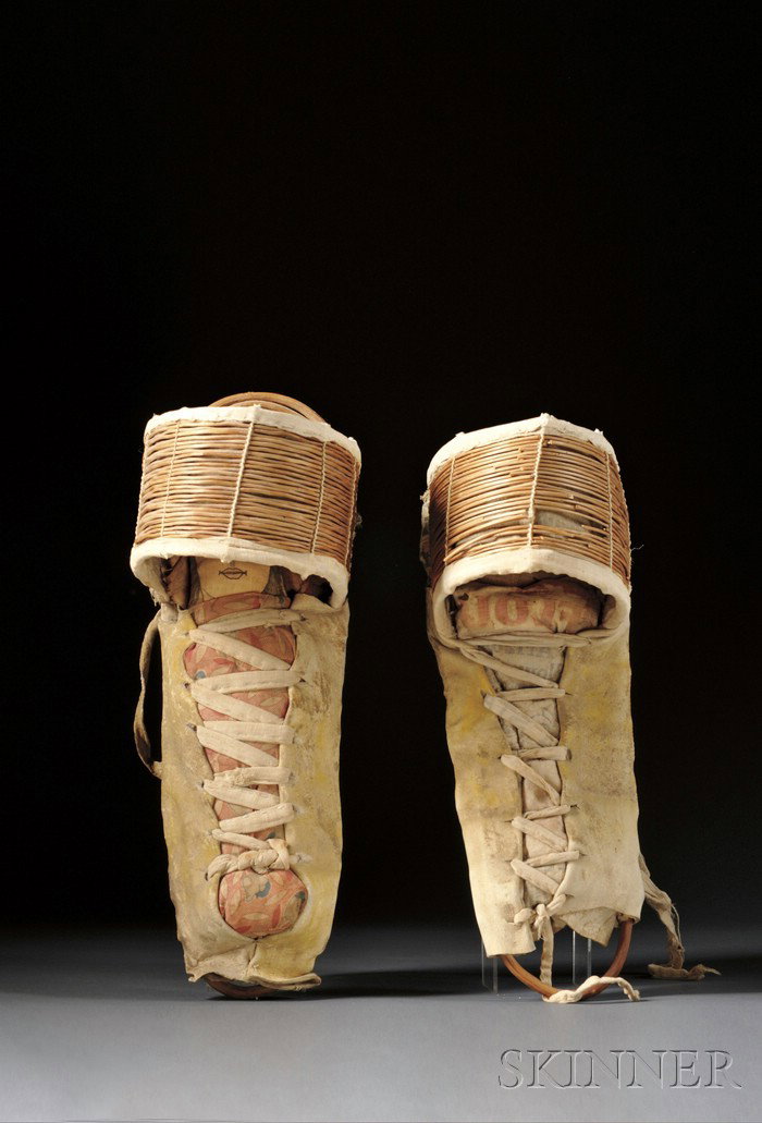 Two Apache Hide and Wood Model Cradles, early 20th: Two Apache Hide and Wood Model Cradles, early 20th century, with reed hoods, traces of yellow pigment, with a commercial cloth doll, (one cradle with damage), lg. to 18 1/2 in.