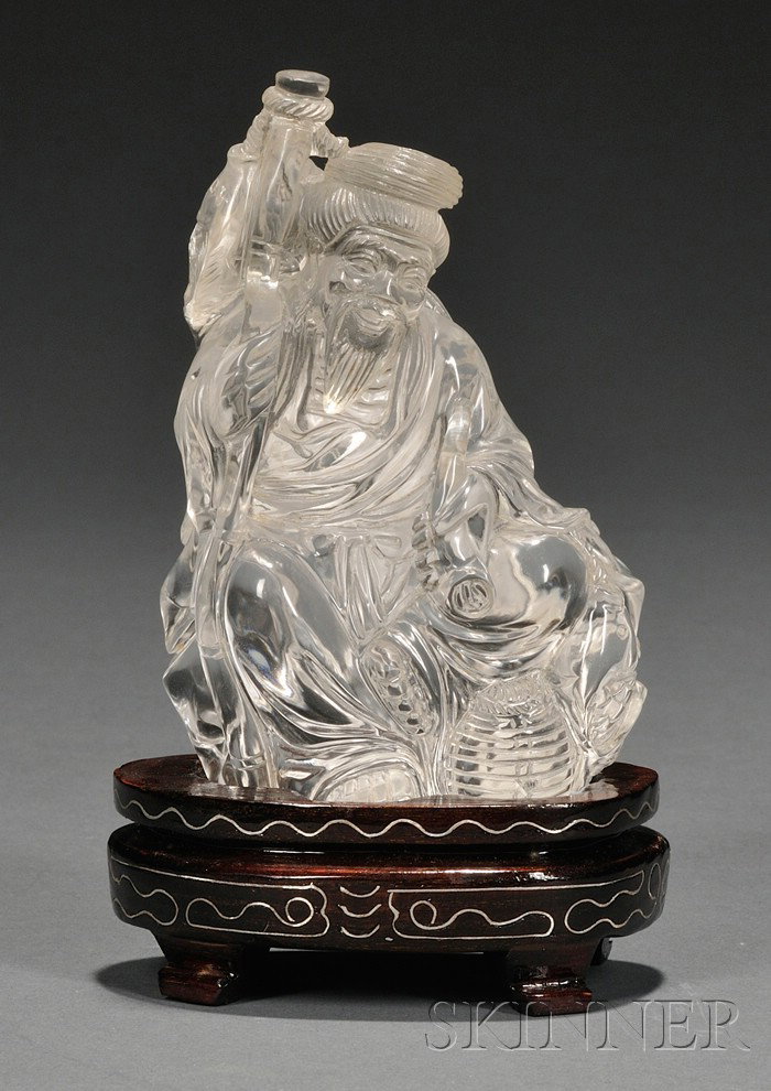 Rock Crystal Carving, China, carved as an old man : Rock Crystal Carving, China, carved as an old man seated on a fish basket, holding a staff in his right hand and a pipe in his left, wood stand with wire design, ht. 4 in.