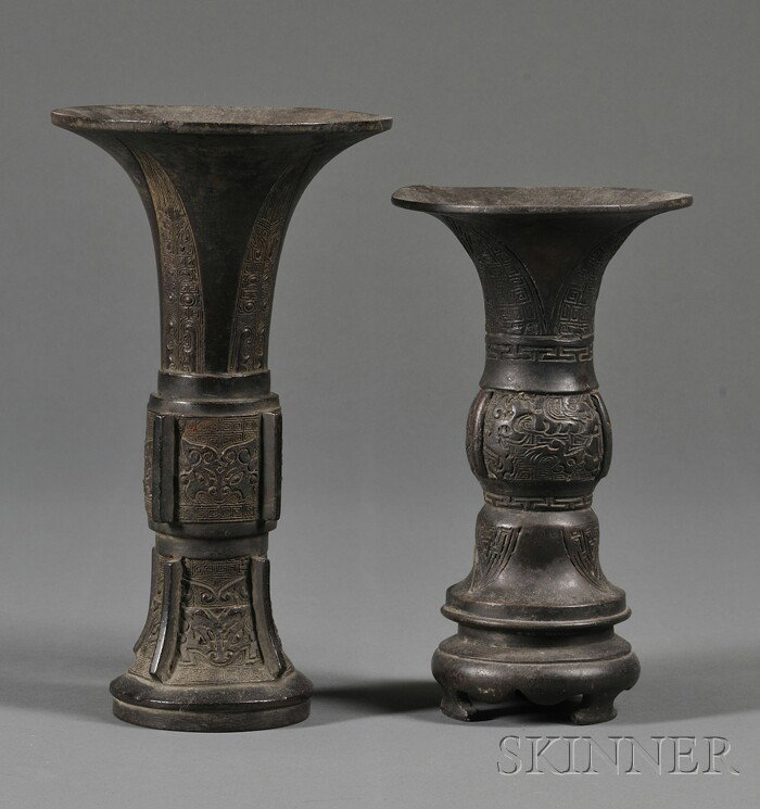 Two Bronze Vases, China, 19th century, both of ar: Two Bronze Vases, China, 19th century, both of archaic drinking vessel gu shape, one tall, crisply cast with bands of stylized taotie masks on a key-fret ground, separated by vertical flanges, below a