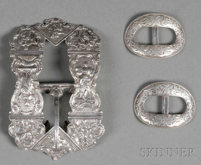 Three Silver Buckles, mid-late 19th century, compr: Three Silver Buckles, mid-late 19th century, comprising an American pair marked B.B. & B. Co., oval, engraved with leafy scrolls, wd. 2, and a Dutch ovoid example, cast with panels of figures, wd. 4 1